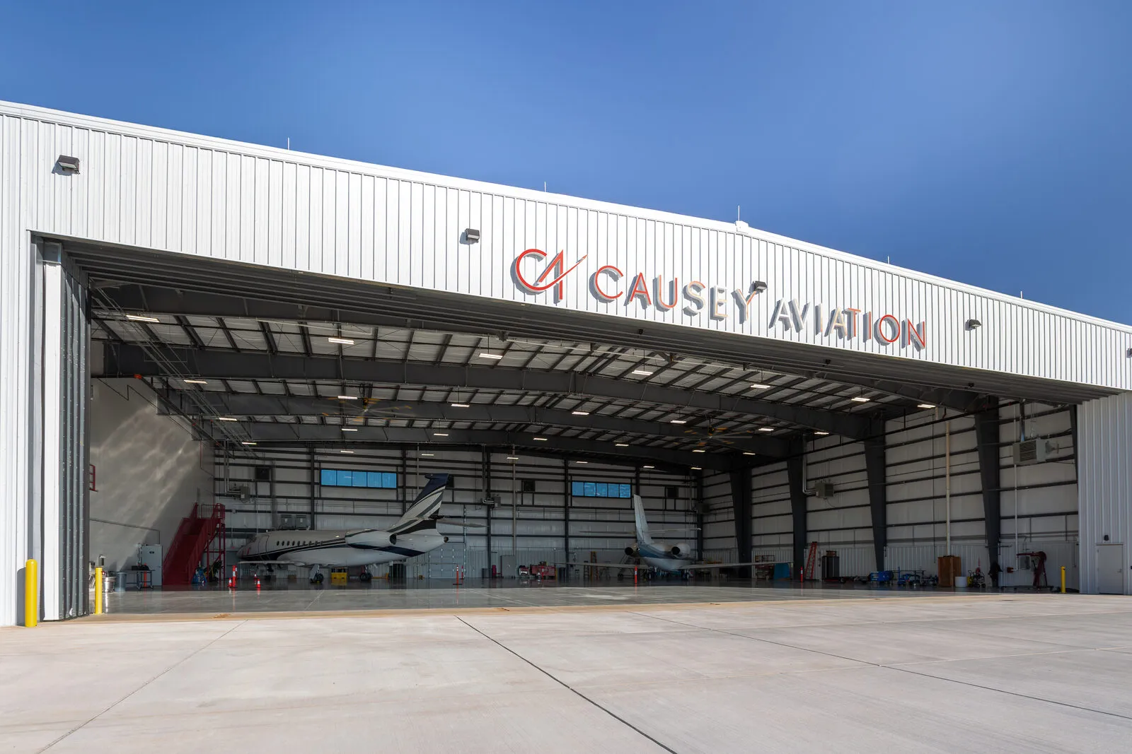 Causey Aviation hangar facility at Greensboro PTI with business jets inside and the 124 ft door open